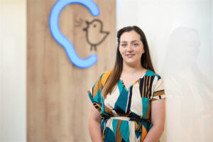 Mitarbeiterin Alexandra Ratiu steht vor einer Wand mit Bagus-Logo