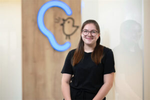 Mitarbeiterin Ines Peemöller steht vor einer Wand mit Bagus-Logo