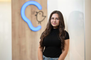 Mitarbeiterin Larissa Buhai steht vor einer Wand mit Bagus-Logo