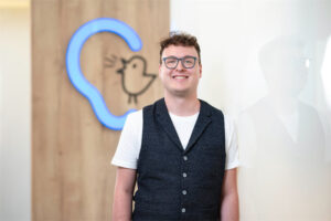 Mitarbeiter Michael Kovacic steht vor einer Wand mit Bagus-Logo