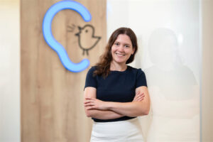 Mitarbeitern Verena Nowak steht vor einer Wand mit Bagus-Logo