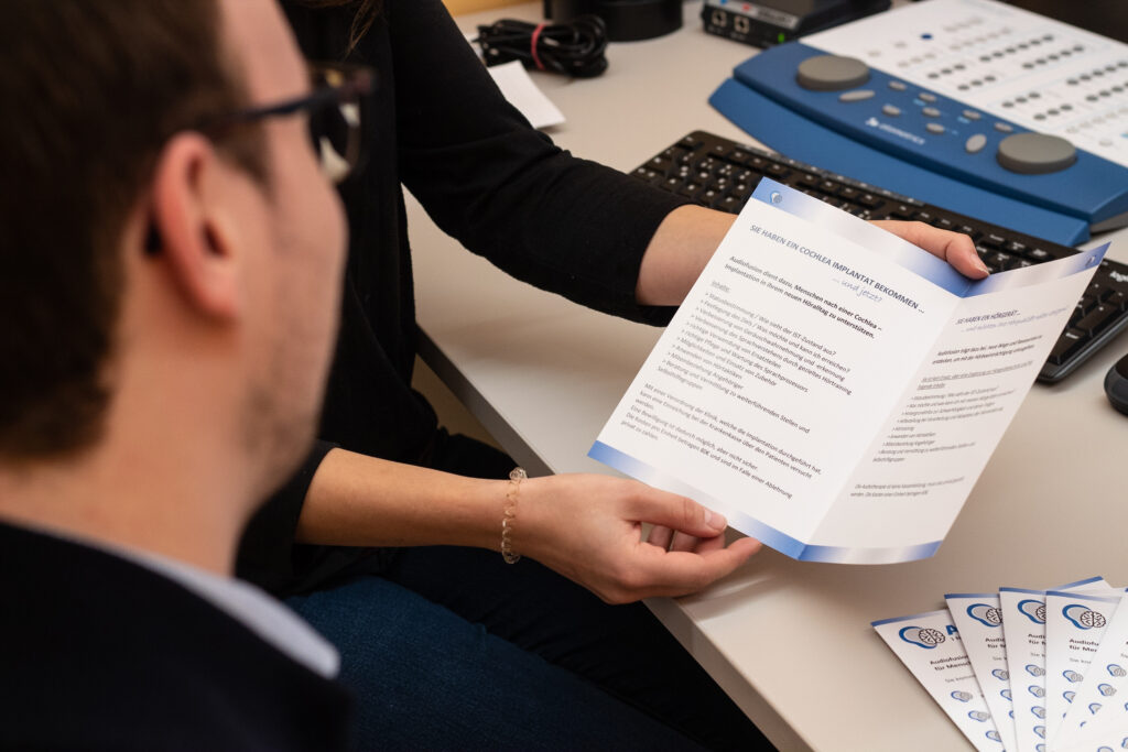 Beratungssituation zwischen zwei Personen mit Leistungsfolder